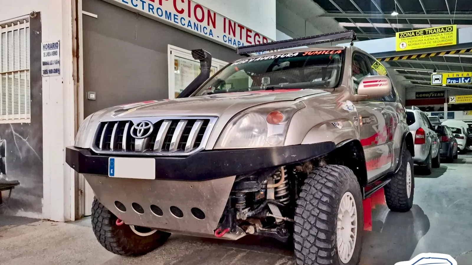Toyota Land Cruiser de raid cubierto de tierra a la puerta del taller